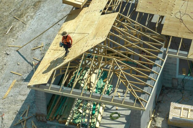 Builders working on roof construction of unfinished residential house with wooden frame structure in Florida suburban area Housing development concept