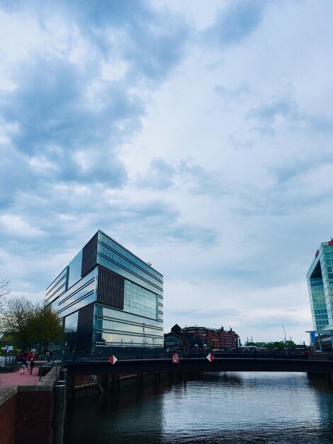 Photo building by river against sky in city