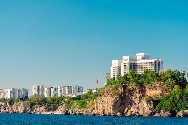 A building on a cliff with a blue sky and a building on the right side.