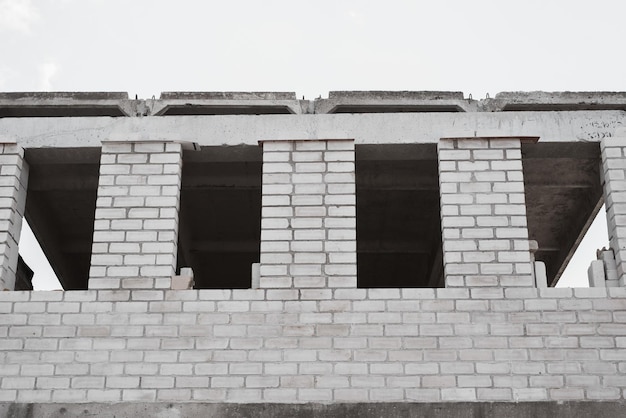 Building under construction gray brick walls and empty window openings outdoors exterior