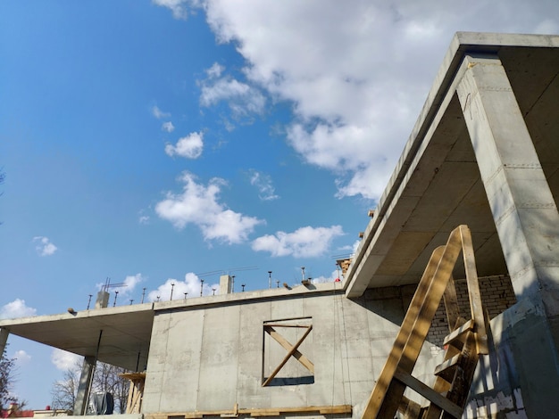 A building under construction with a blue sky and clouds in the background.