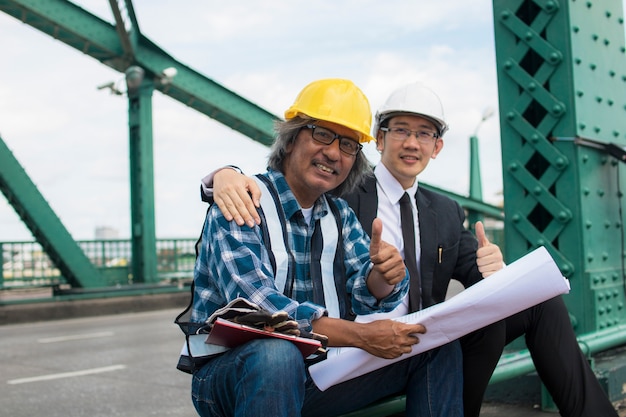 Photo building contractor and engineer sitting and showing thumb to admire at construction