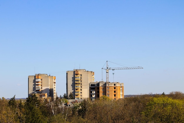 Building crane and building under construction against blue sky