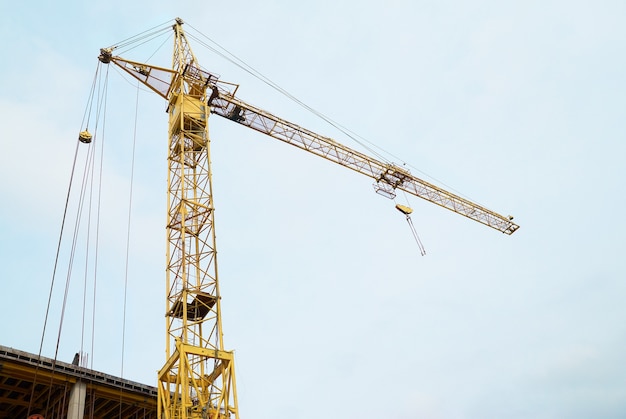 Building crane on construction site with the blue sky