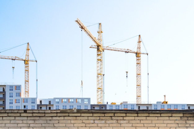 Building cranes and building under construction behind the fence