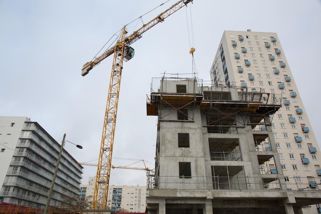 Building and cranes under construction against grey sky