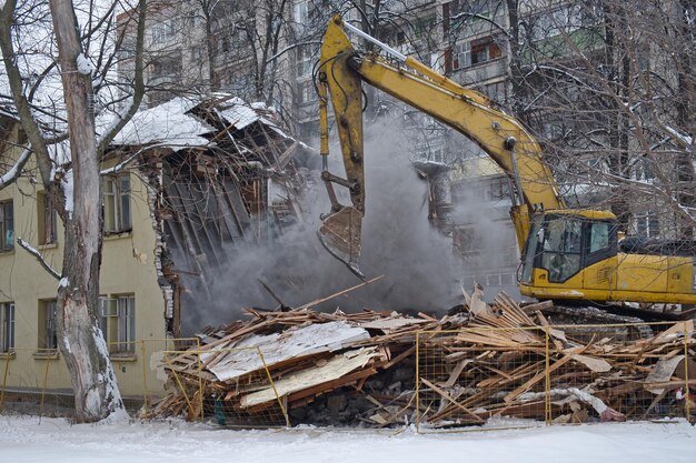 Building demolition Excavator breaks old house Industrial cityscape with destroy process