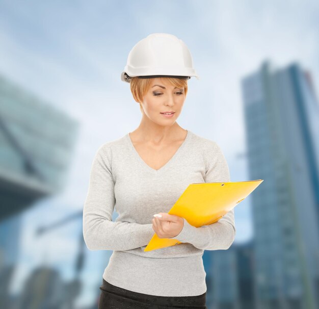 building, developing, consrtuction, architecture concept - female contractor in white helmet with blueprint