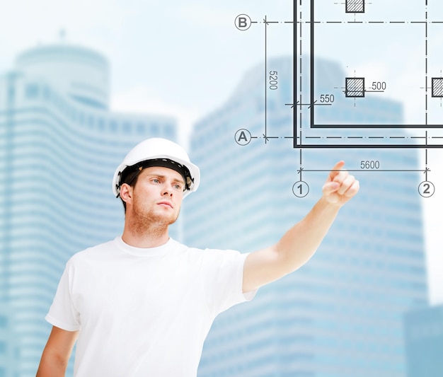 building, developing, consrtuction and architecture concept - male architect in helmet pointing to blueprint on virtual screen