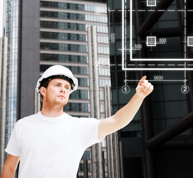 концепция строительства, разработки, строительства и архитектуры - мужчина-архитектор в шлеме, указывающий на план на виртуальном экране