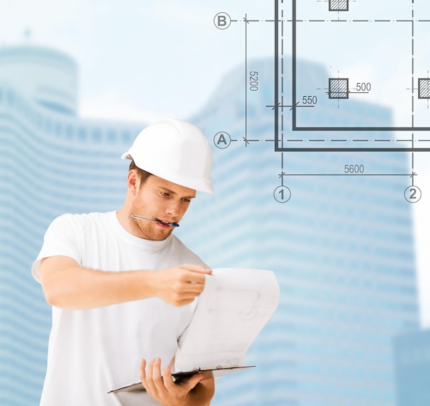 концепция строительства, разработки, строительства и архитектуры - мужчина-архитектор в белом шлеме, смотрящий на план