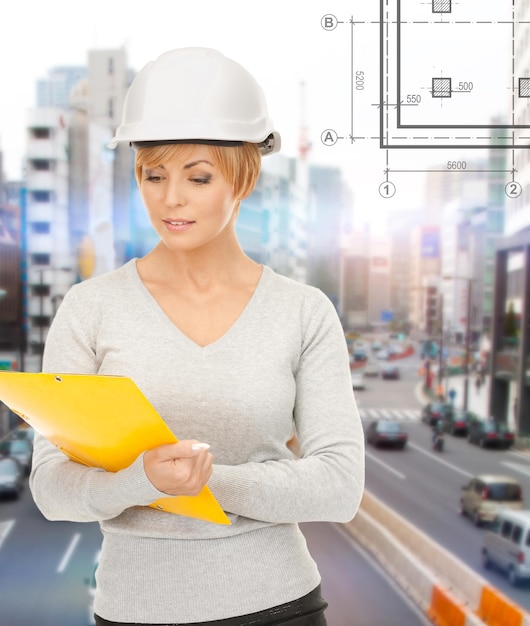 建築、開発、建設、建築のコンセプト-フォルダー付きヘルメットの女性請負業者