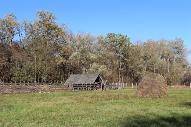 Photo a building in a fenced in field with a large rock in front of it