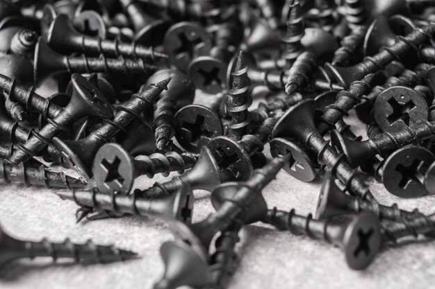 Building hardware background Pile of self tapping black screws Close up Selective focus