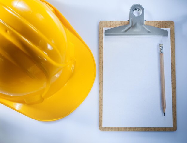 Building helmet clipboard pencil on white background