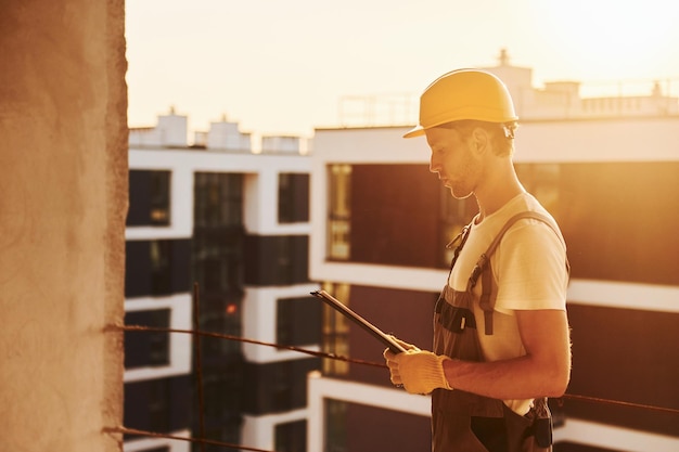 Building of modern city Young man working in uniform at construction at daytime