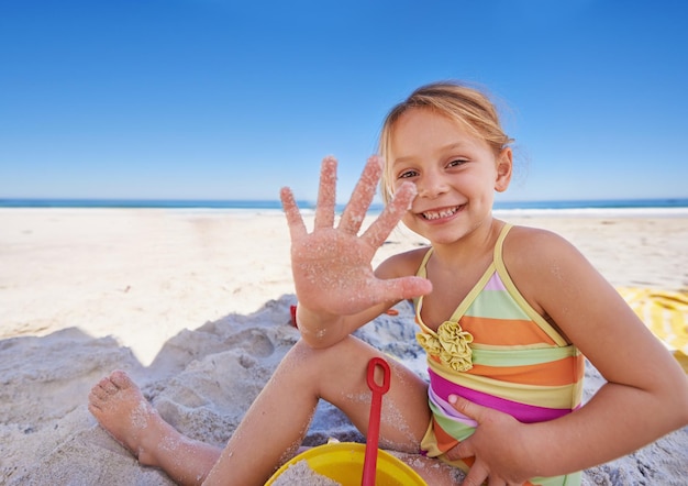 Building the most awesome sandcastle ever a cute little girl sitting on the sand at the beach with her bucket and spade