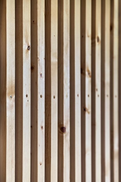 Building wall decorated with wooden furring made of thin light planks on house terrace close up