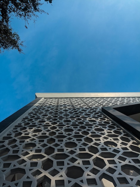 a building with a geometric pattern on the side and a blue sky behind it