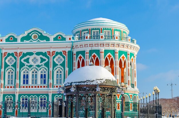 A building with a green and red facade and a gazebo in the snow