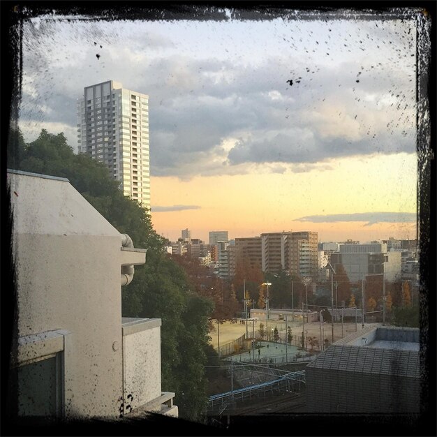 Photo buildings against cloudy sky in city during sunset