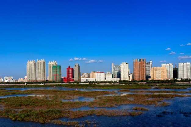 Buildings by city against blue sky