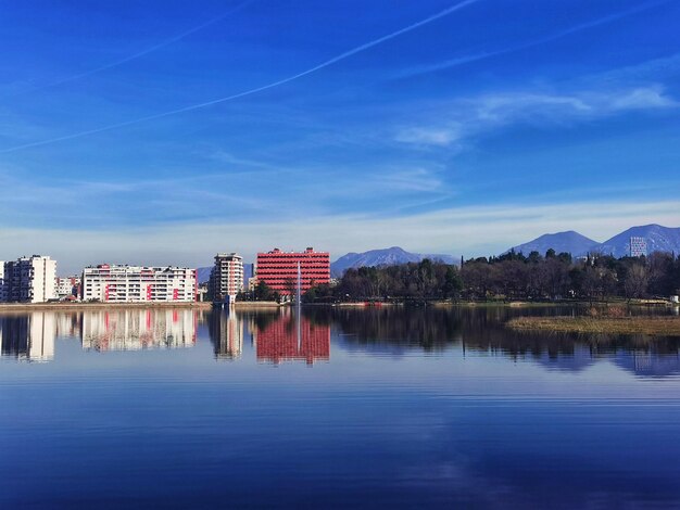 Buildings by lake against blue sky