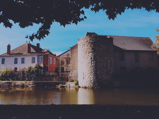 Buildings by lake in town against sky