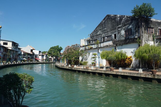 Buildings by river against clear blue sky