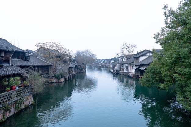 Buildings by river against clear sky