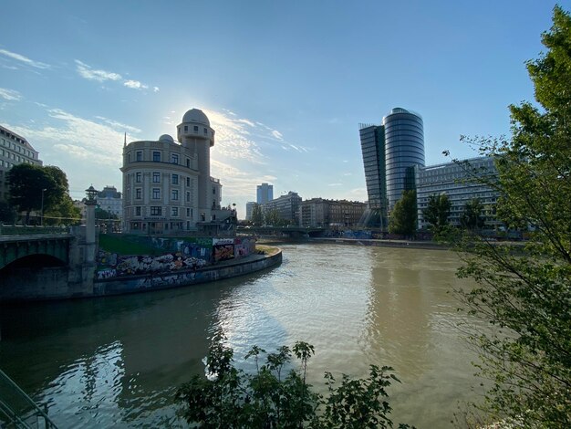 Buildings by river against sky in city