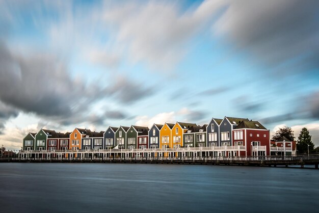 Photo buildings by river against sky in city