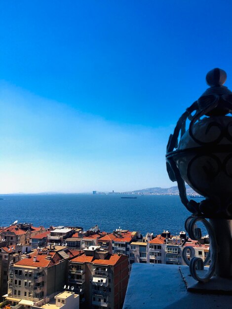 Buildings by sea against blue sky