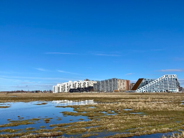 Buildings by sea against blue sky