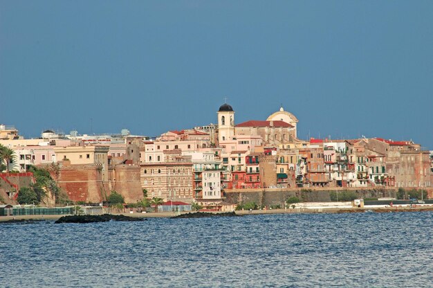 Photo buildings by sea against clear blue sky