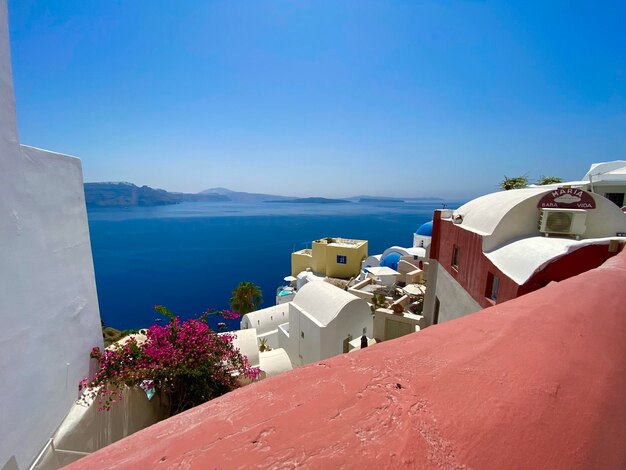 Buildings by sea against clear blue sky