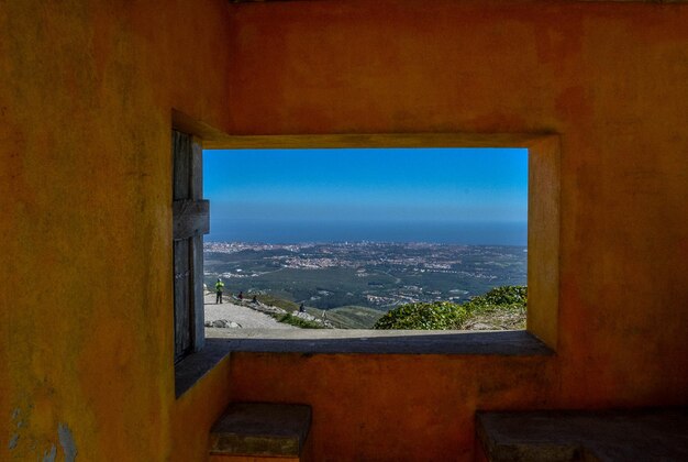 Buildings by sea against sky seen through window