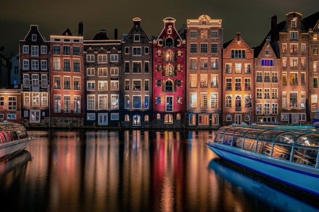 Photo buildings in city by river against cloudy sky