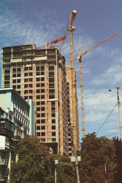 Buildings and cranes on blue sky background