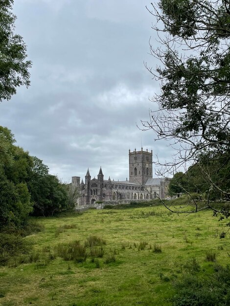 Buildings on field against cloudy sky