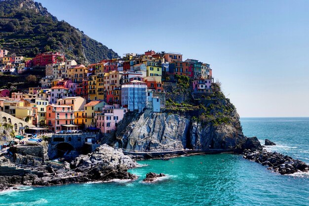 Photo buildings on mountain by sea against clear blue sky