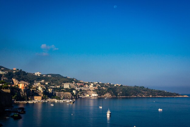 Buildings on mountain by sea at dusk