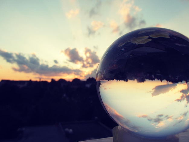 Foto edifici e cielo riflessi su una palla di cristallo durante il tramonto