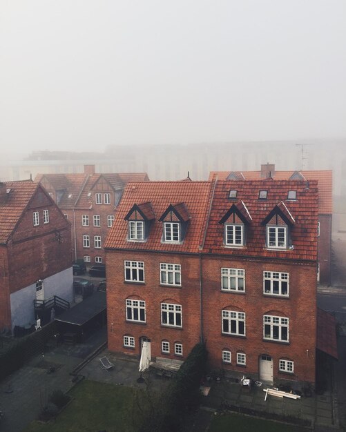 Photo buildings in town against sky during foggy weather
