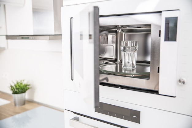 Built-in microwave oven  in the kitchen with a cup of pure water.