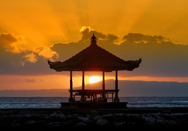 Built structure on beach against sky during sunset