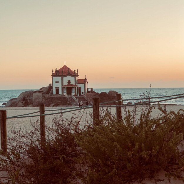 Foto struttura costruita sulla spiaggia dal mare contro il cielo durante il tramonto