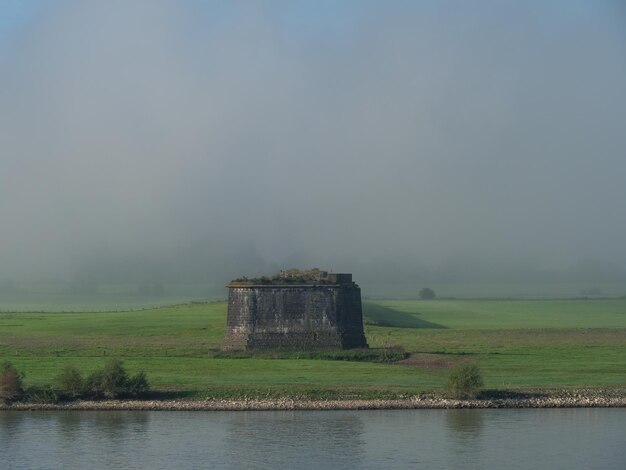 Built structure on field by lake against sky