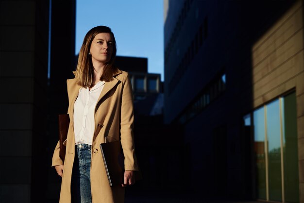 Photo buiness woman goes to work and holding laptop in hands