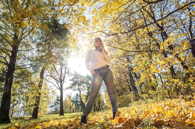 Buiten close-up portret mooi blond meisje ontspannen op de grond in het herfstbos op zonnige warme dag